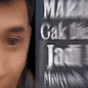 a blurry picture of a man 's face with a sign in the background that says ' make cak ' on it .