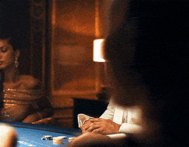 a man in a tuxedo sits at a poker table with chips on it