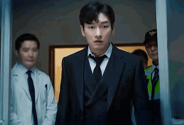 a man in a suit and tie is standing in front of a police officer and a doctor