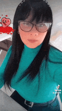 a woman wearing glasses and a blue sweater is standing in front of a table .