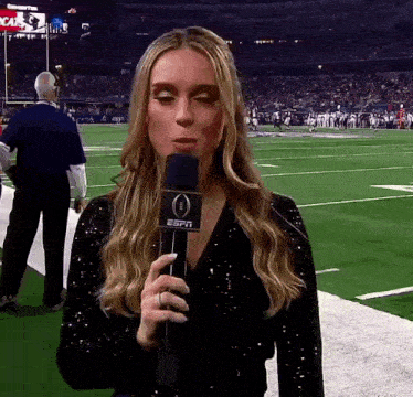 a woman is holding a espn microphone in front of a football field