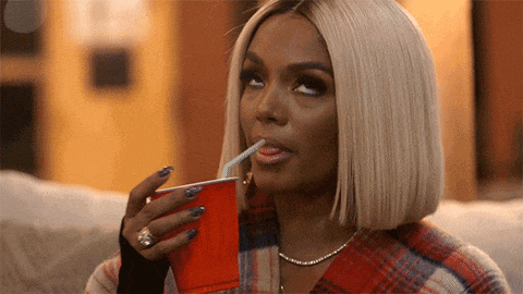 a woman drinks from a red cup with a straw