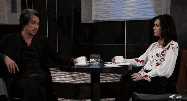 a man and a woman are sitting at a table and talking