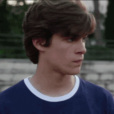 a close up of a young man 's face wearing a blue t-shirt