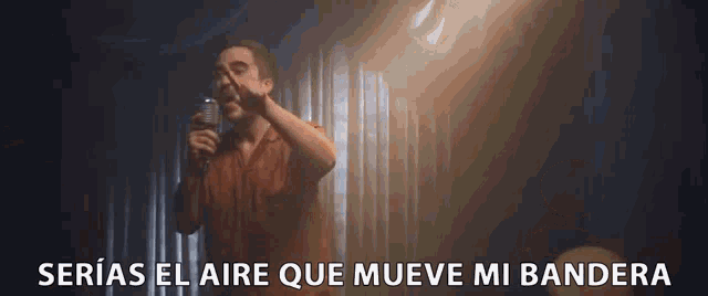 a man singing into a microphone with the words serias el aire que mueve mi bandera written below him