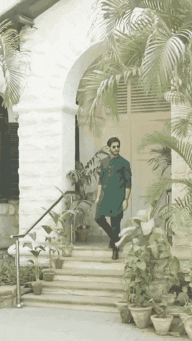 a man in a green kurta is walking down stairs in front of a building