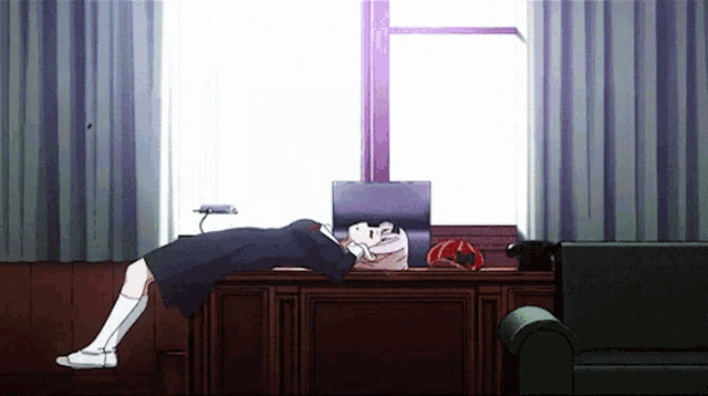 a girl laying on a desk in front of a laptop