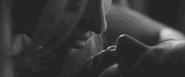 a black and white photo of a man kissing a woman on the neck .