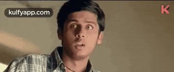 a young man in a plaid shirt is making a funny face and looking up .