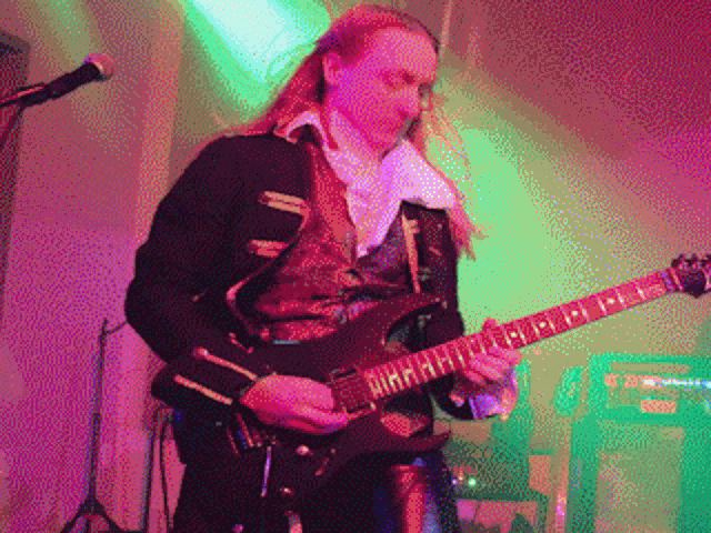 a man in a black jacket is playing a guitar with the letter r on it