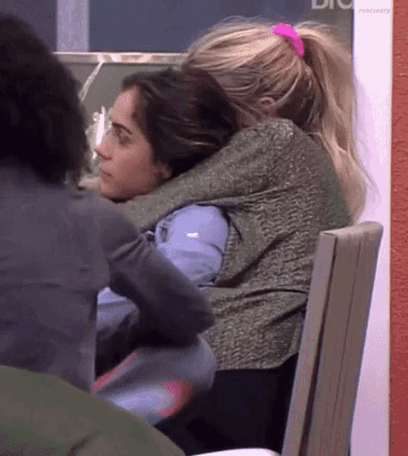 a woman is hugging another woman in front of a sign that says rootseeker