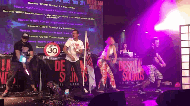 a group of people dancing on a stage with a sign that says 30
