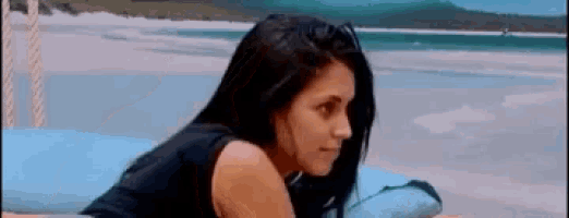 a woman is laying on a bed on the beach looking at the camera .