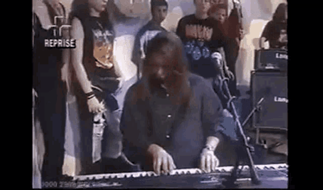 a man is playing a keyboard in front of a crowd of people .
