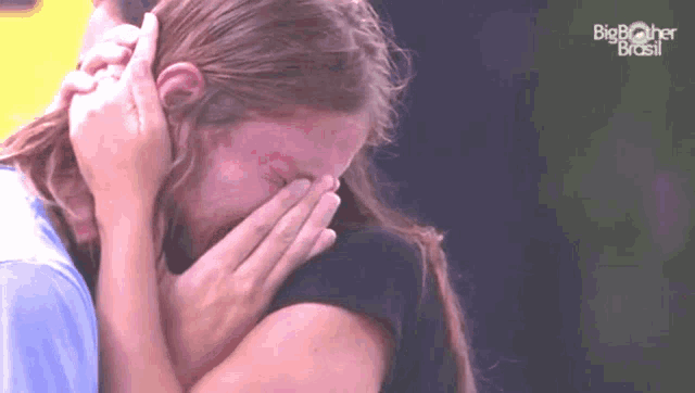 a woman is crying while being hugged by a man with big brother brasil written on the screen