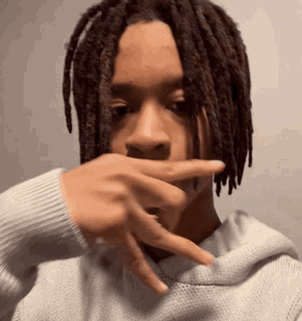 a man with dreadlocks covering his mouth with his hand