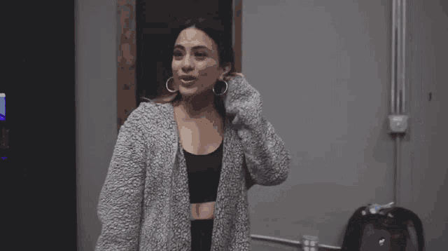 a woman wearing a grey cardigan and hoop earrings