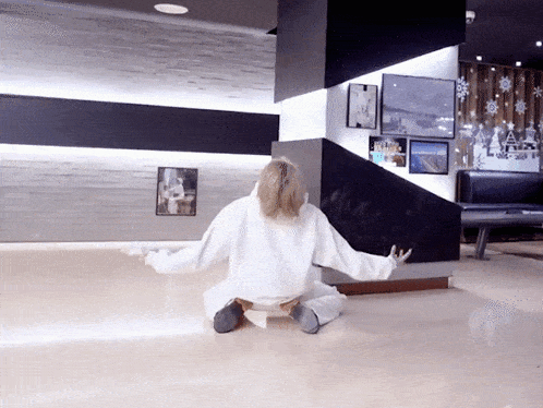 a woman in a white sweatshirt is sitting on the floor
