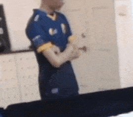 a blurry picture of a man in a blue shirt standing in a room