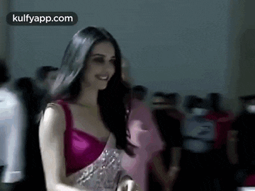 a woman in a pink dress is standing in front of a crowd .