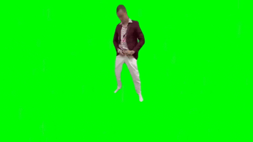 a man in a suit and tie is standing on a green screen with his hands on his hips .