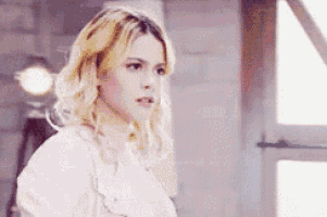 a woman with blonde hair is wearing a white shirt and looking at the camera .