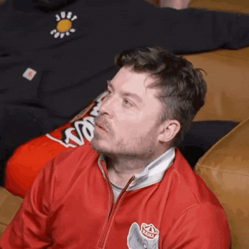 a man wearing a red jacket with a lion on it