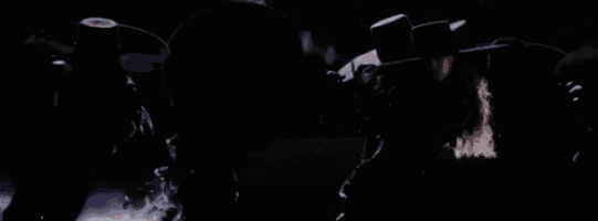 a group of people are riding a roller coaster in a dark room with smoke coming out of it .