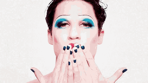 a close up of a woman blowing a kiss with her hands .