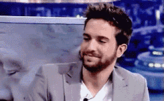 a man with a beard is wearing a suit and a white shirt and smiling .