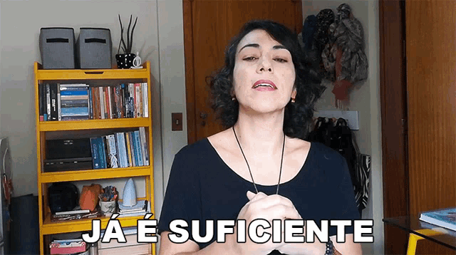 a woman stands in front of a yellow bookshelf and says ja e suficiente