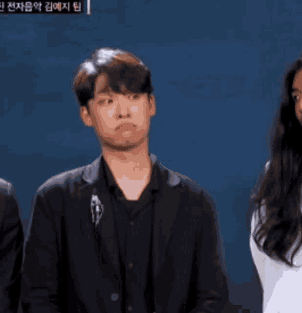 a man in a black suit is making a funny face while standing next to a woman