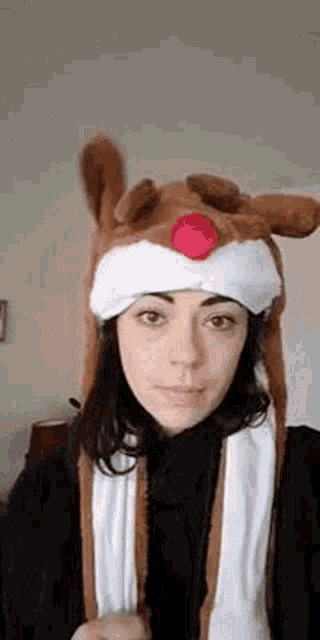 a woman wearing a reindeer hat with a red nose .