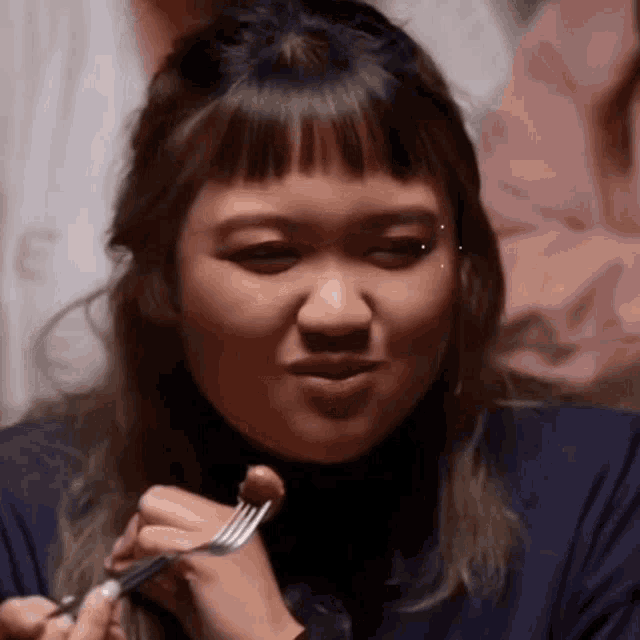 a woman is holding a fork in her hand and making a face