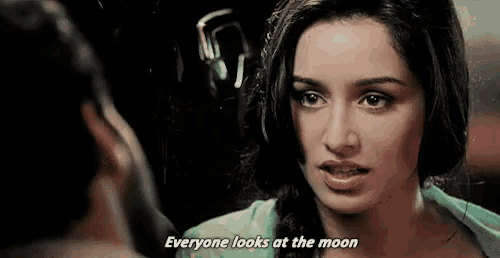 a woman is talking to a man in a dark room and says `` everyone looks at the moon '' .