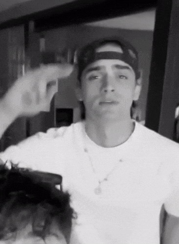 a black and white photo of a man wearing a baseball cap and a white shirt .