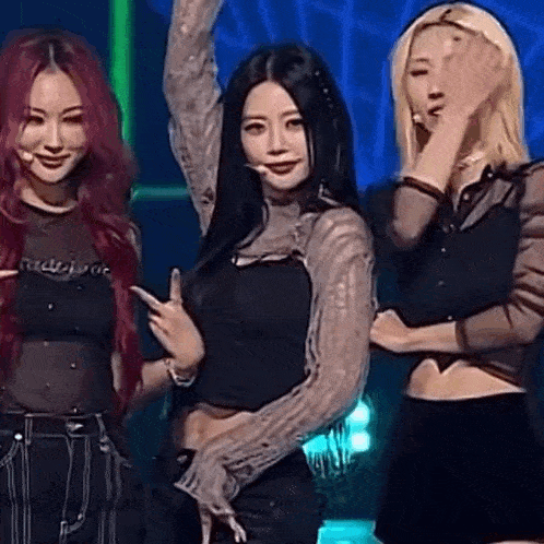 three women are standing next to each other on a stage and one of them is wearing a crop top .
