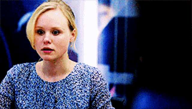 a woman in a blue floral shirt is looking at something