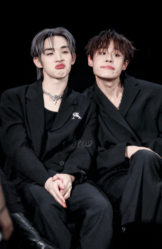 a couple of boys sitting next to each other with one wearing a jacket with the letter s on it