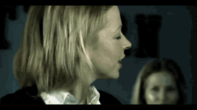 a close up of a woman 's face in a dark room with the letter x in the background