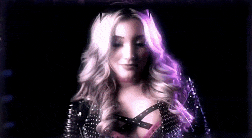 a woman is standing in a wrestling ring wearing a choker and a black jacket .