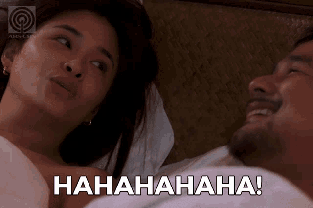 a man and a woman are laying in bed and the woman is laughing and the man is laughing with the words hahahaha
