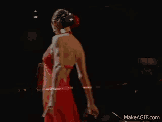 a woman in a red dress is dancing on a stage in a dark room .