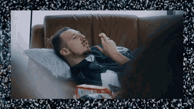 a man laying on a couch with a box of chips in front of him that says aos