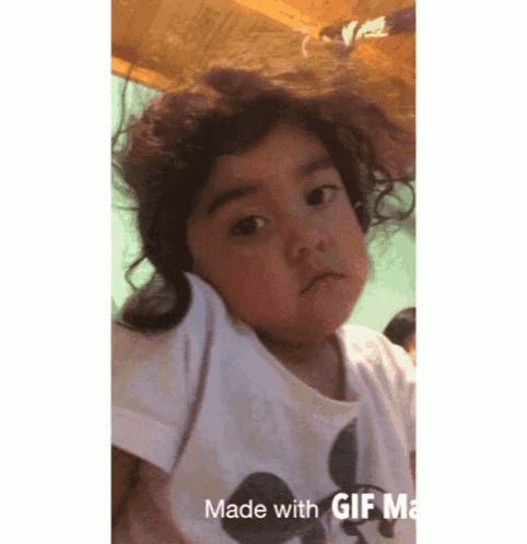 a little girl wearing a mickey mouse shirt is making a funny face