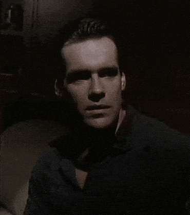 a man in a black shirt is standing in a dark room .
