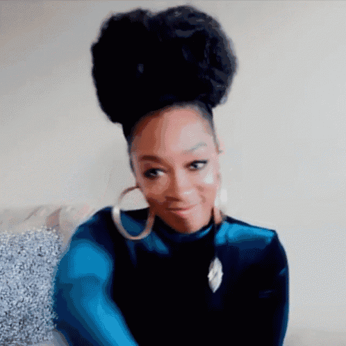 a woman with a bun in her hair is wearing hoop earrings and a blue shirt .