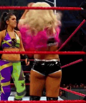 a woman in a pink top is standing in a wrestling ring with other women
