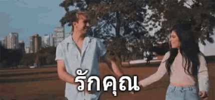 a man and a woman are holding hands in a park in a foreign language .