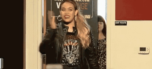 a woman is standing in a doorway wearing a leather jacket and a skull shirt .